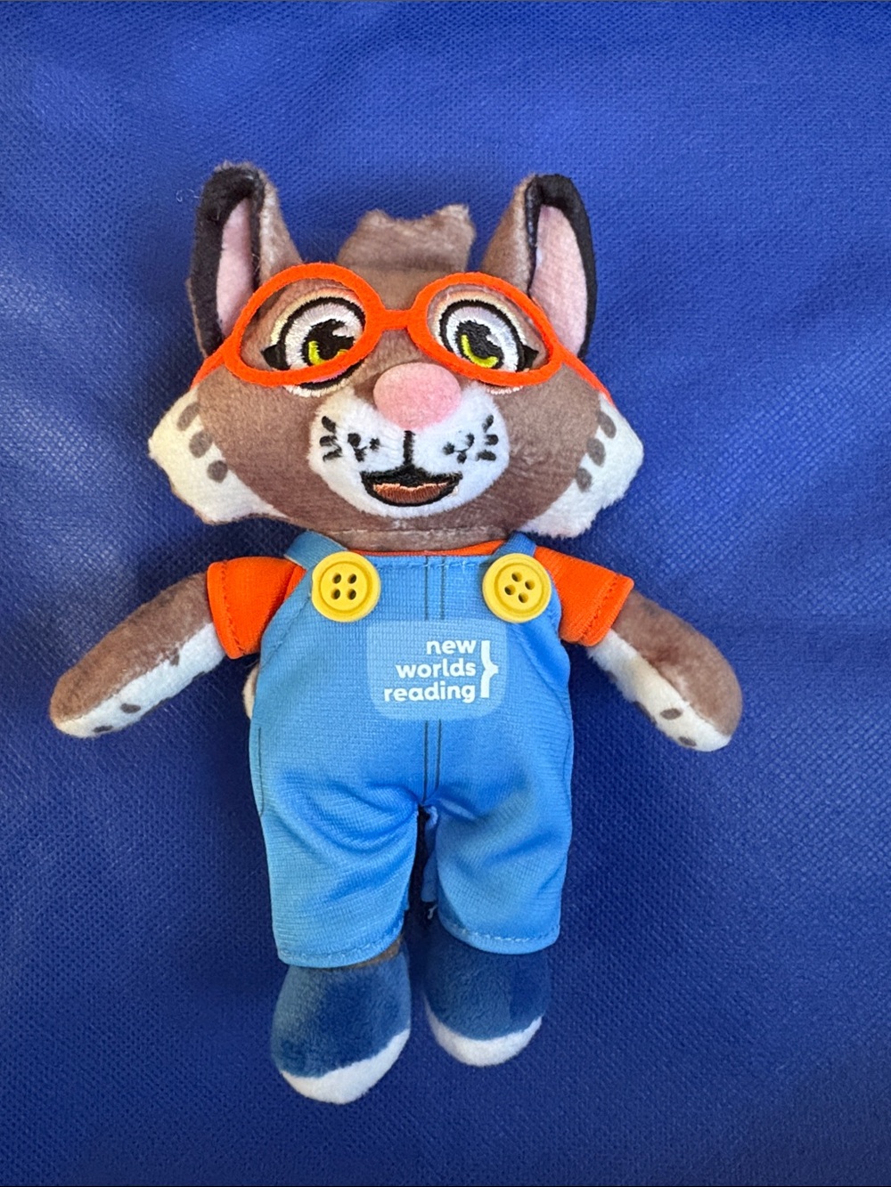 New Worlds Reading Brown Cat Plush Toy with Blue Overalls and Orange Glasses